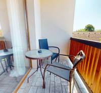 A balcony in a 2-room apartment with a view of the surrounding greenery and rooftops.