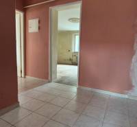 The hallway in a 3-room apartment with white floor tiles and pink walls.