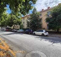 Under Párovce in Piešťany, there are trees lining the road by the three-story apartment buildings.