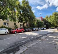 Pod Párovcami Street in Piešťany with cars parked in front of a 3-room apartment in the shade of trees.
