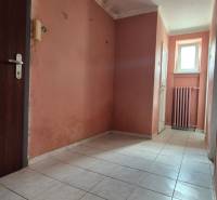 A hallway with light-colored tiles in a 3-room apartment, light pink walls, radiator.