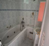 Bathroom in a 3-room apartment with a bathtub, sink, and tiles in muted colors.