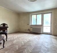 A room in a 3-room apartment with a wooden floor, old furniture, and a large window.