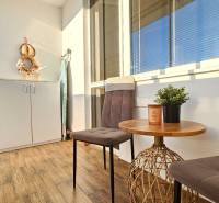A balcony in a one-room apartment with two chairs, a table, and a storage cabinet.