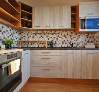 Kitchen in a studio apartment with light wood, built-in oven, and microwave.
