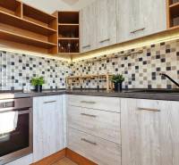 Kitchen in a studio apartment with wooden cabinets, tiles, and an oven.