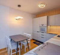 A kitchen in a 3-room apartment with light furniture and wooden flooring.