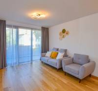 Living room with wooden flooring, gray furniture, and a large window in a three-room apartment.