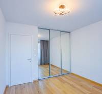 A room with a wooden floor, a mirrored wardrobe, and simple lighting in a 3-room apartment.