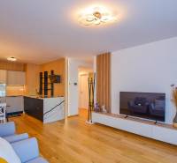 Living room with an open kitchen; wooden floor, dining table, television, 3-room apartment.