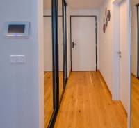 A hallway with mirrored wardrobes in a 3-room apartment, white walls, wooden floor.