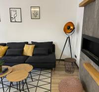 Living room in a 3-room apartment with a black sofa and decorative lighting.