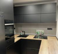 A kitchen in a 3-room apartment with black cabinets and a wooden countertop.