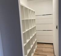 Built-in wardrobe with shelving system in a 3-room apartment, light wooden floors, white walls.