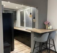 Stylish kitchen with wooden flooring and a bar counter in a 3-room apartment.