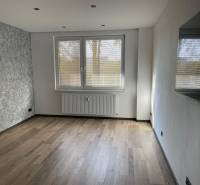 A living room in a three-room apartment with gray walls and light floors.