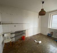 An empty kitchen with simple equipment in a 3-room apartment, white walls, radiator.