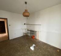An empty kitchen in a 3-room apartment with an unusual chandelier and an unfinished floor.