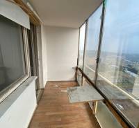 Glazed loggia with wooden flooring in a 3-room apartment, view of the exterior.