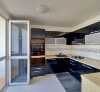 A kitchen with dark cabinets and built-in appliances in a three-room apartment.