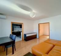Living room in a three-room apartment with a wooden decor floor and a dining table.