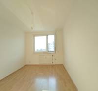 An empty room with a large window, white walls, and a wooden-patterned floor, 3-room apartment.