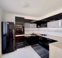 A kitchen in a 3-room apartment with black glossy cabinets and a corner stove.