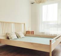 A bedroom with light wooden furniture and a large window in a 2-room apartment.