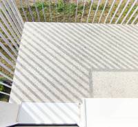 A balcony with a concrete floor and metal railing, facing the garden.