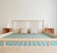 A bright bedroom with a wooden bed and pillows in a two-room apartment.