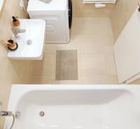 Bathroom with a bathtub, sink, washing machine, and ladder radiator in a 2-room apartment.