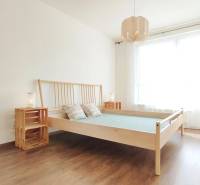 A bright bedroom with a wooden bed and nightstands in a two-room apartment.