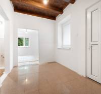 Interior of a family house with tiles, a wooden ceiling, and white walls.