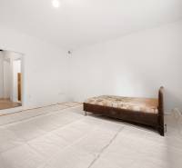 Bright room in a family house with a bed and an open passage to another part.