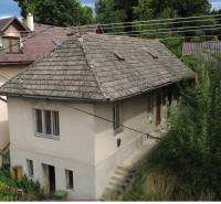 A family house under Bôd Bánoš in Banská Bystrica with a sloped roof and a garden.