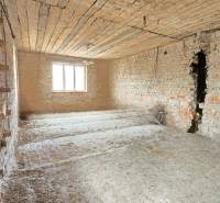 Unrenovated room with brick walls and a window in a family house.