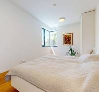 Bright bedroom in a family house with a large window, a painting, and a plant.