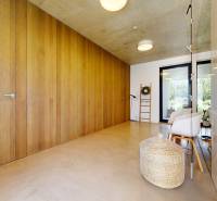 A minimalist hallway in a family house with a wooden wall, a wicker basket, and modern chairs.