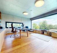 Home office with wooden flooring, large windows, and shelving units.