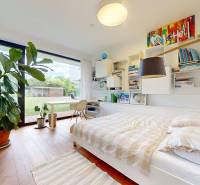 Bright bedroom in a family house with a bed, a plant, and a view of the garden.