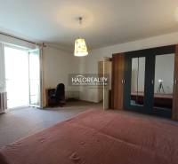 A spacious room in a one-room apartment with a bed, a wardrobe, and balcony doors.