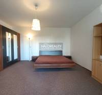 A stylish interior of a studio apartment with a bed, built-in wardrobe, and shelves.
