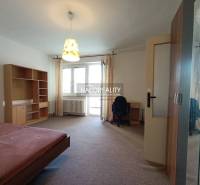A bedroom in a one-room apartment with a built-in wardrobe and a desk.
