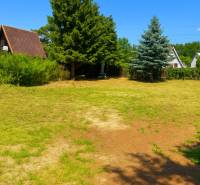 A garden in Lozorno with greenery, trees, fences, and a country house in the background.