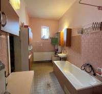 A bathroom in a family house with a bathtub, sink, and cabinets, cozy furnishings.