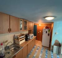 A kitchen in a family house with wooden cabinets, a microwave, and a refrigerator.