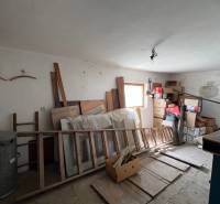 A mess in a room of a family house with stored cabinets, boxes, and wooden frames.