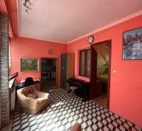 A living room in a family house with orange walls, an armchair, and checkered flooring.