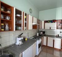 A kitchen in a family house with brown and white cabinets and a coffee maker.