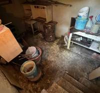 An old basement of a family house with a table, buckets, and tools in a dark room.